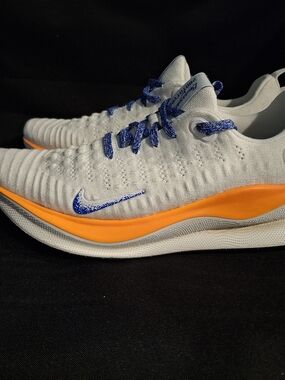 Nike White Flyknit Trainers with Orange Midsole and Blue Accents